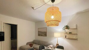 Un coin repas comprenant une table ronde, des chaises, un luminaire suspendu, un canapé, une lampe et une plante.