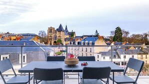 Ein Balkon mit Tisch und Stühlen, der einen Blick auf eine Stadtlandschaft mit historischen Gebäuden und einer Kirche bietet.