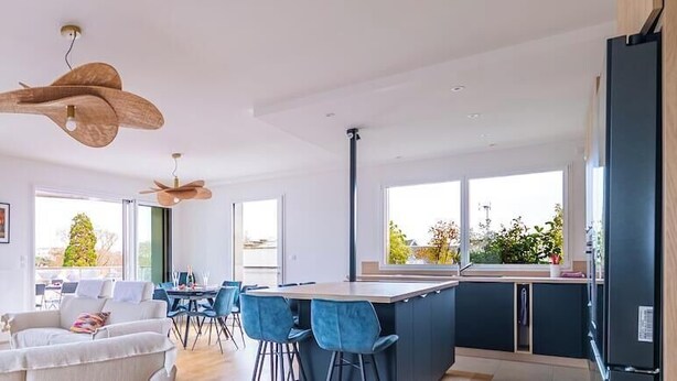 Ein modernes Wohnzimmer mit Sofa, Essbereich und Küche.