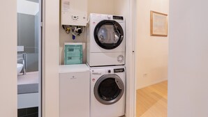 A laundry room with two stacked washing machines, a water heater, and a sink. - Filippini 10 (Verona)
