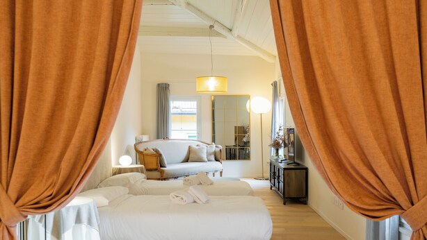 A bedroom with a bed, a sofa, a bedside table, a lamp, and curtains. - Filippini 10 (Verona)
