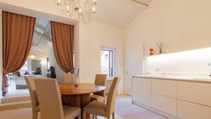 A modern kitchen with a dining area, featuring a round wooden table, beige chairs, and a chandelier. - Filippini 10 (Verona)