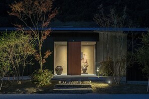 A modern building with a large entrance, a wooden door, and a large vase on the steps. - KANSHUKUEN ESHIKOTO (Eiheiji)