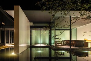 A modern interior with glass walls, a dining area, and a reflective pool. - KANSHUKUEN ESHIKOTO (Eiheiji)