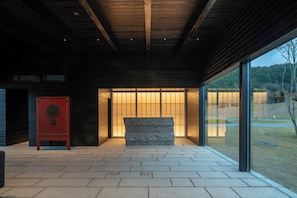 A modern building with a stone bench, a red cabinet, and large glass windows.