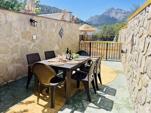 An outdoor patio with stone walls, a table set for dining, and a view of mountains. - Casa Mago de Oz by At Home Costa del sol (Alfarnate)