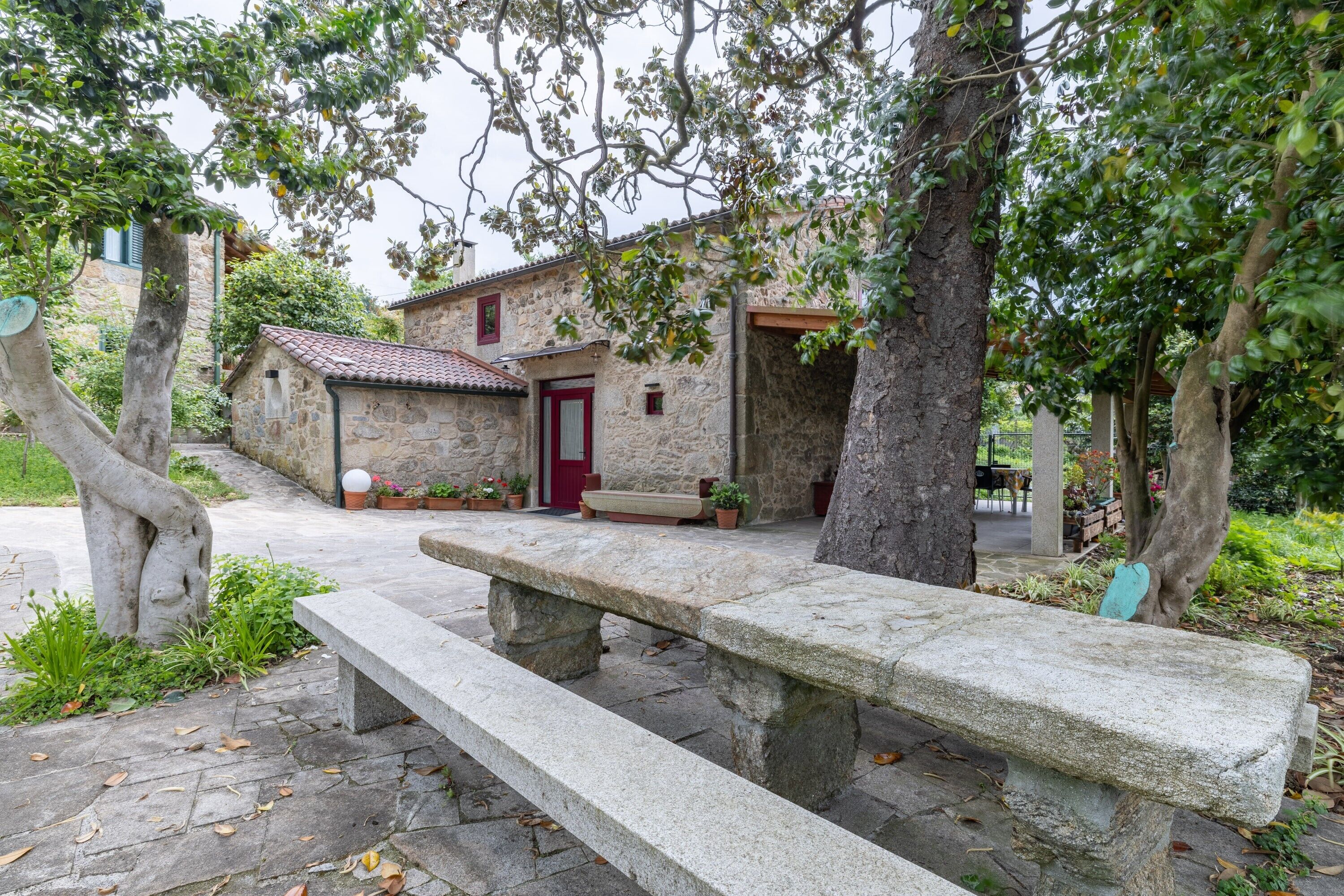 A stone building with a red door, a bench, and potted plants.