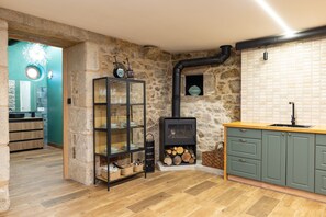 A kitchen with a stone wall, a wooden floor, a glass cabinet, and a stove. - Holiday Home 'Vagalume' with Mountain Views, Wi-Fi and Air Conditioning (Sobredo)