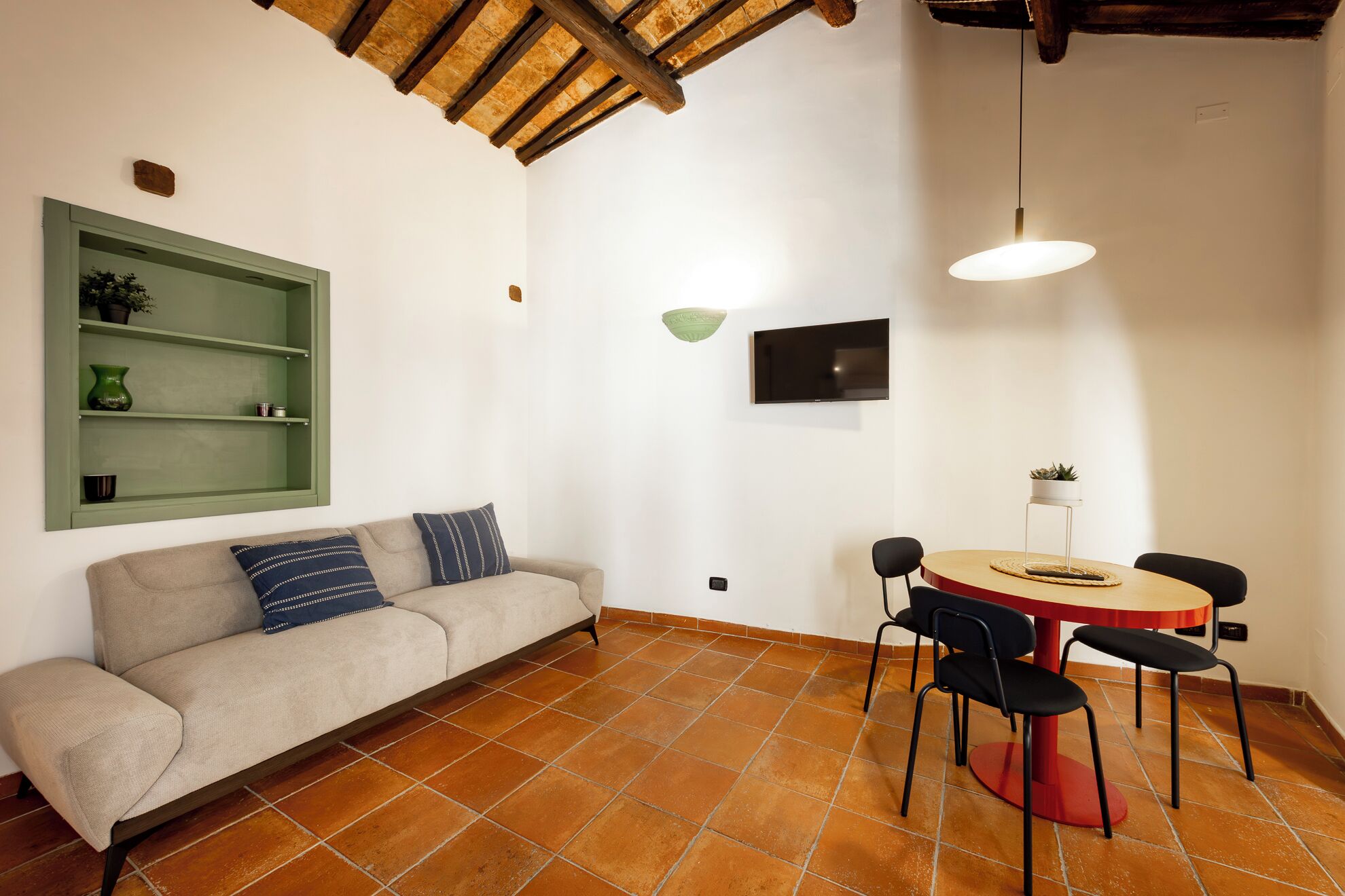 A room with a sofa, a dining table with chairs, a TV, and a green shelf.