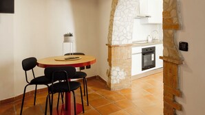 A dining area with a round table and chairs, a hanging light fixture, and a stone archway leading to a kitchen. - Light on the Cathedral: Apartment in the heart of the historic center with a view (Tivoli)