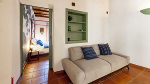 A living room with a sofa, a green shelf, and a door leading to another room. - Light on the Cathedral: Apartment in the heart of the historic center with a view (Tivoli)