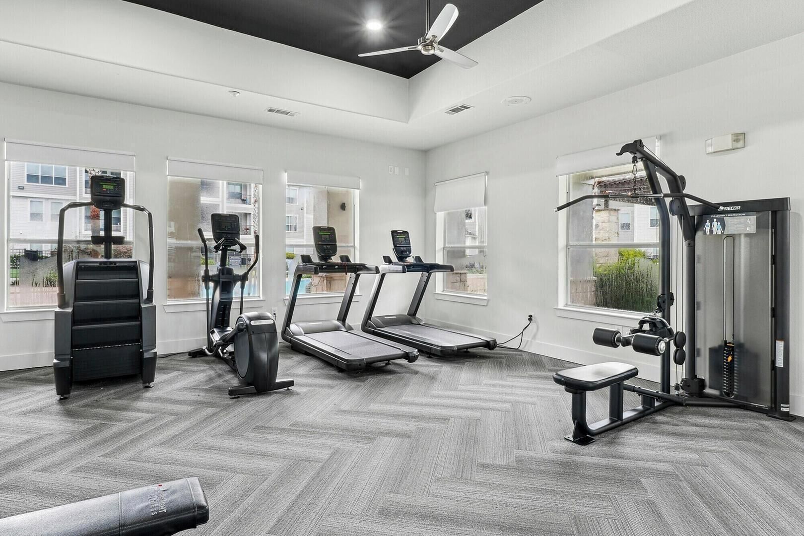 Una palestra con tapis roulant, una macchina per pesi e una ventola a soffitto.