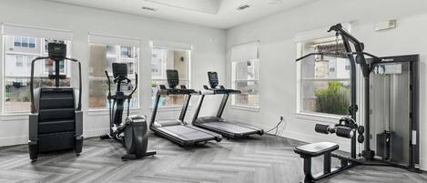 A gym with treadmills, a weight machine, and a ceiling fan.