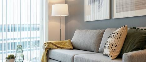A modern living room with a grey sofa, a floor lamp, and a glass coffee table.