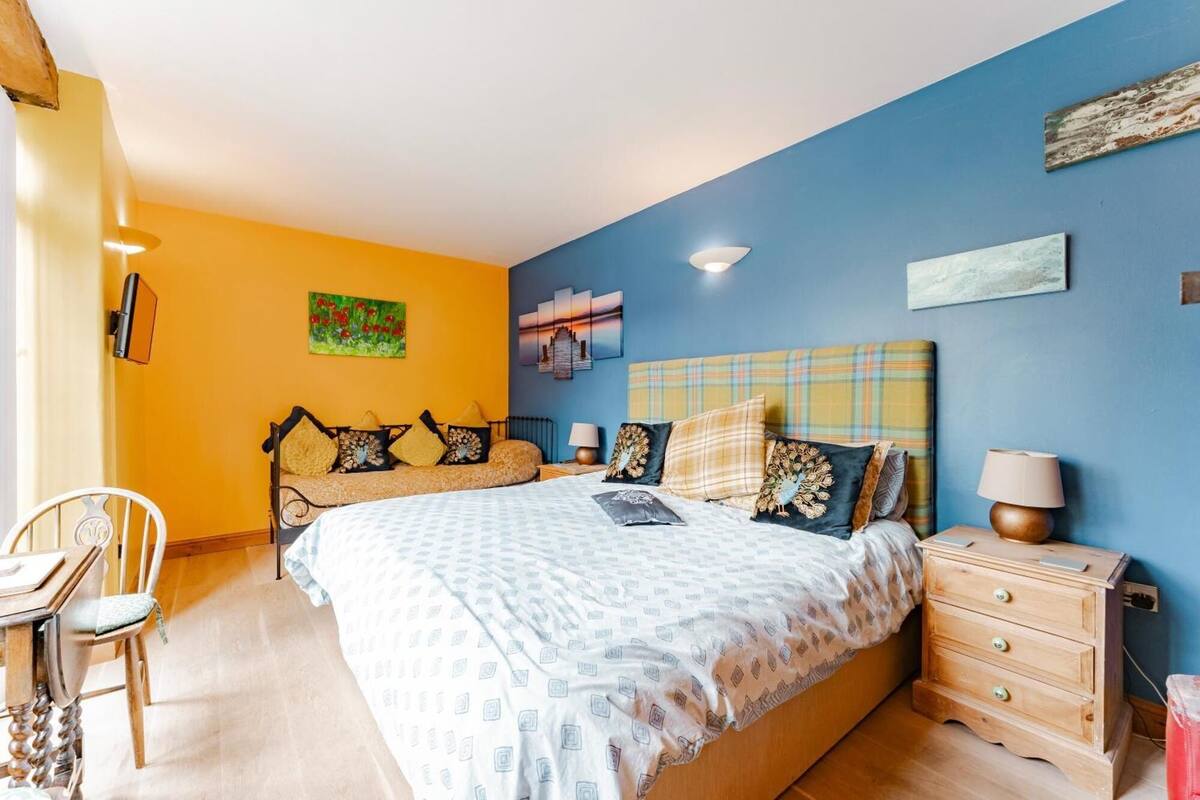 Un dormitorio con cama, mesitas de noche, una silla y obras de arte en las paredes.