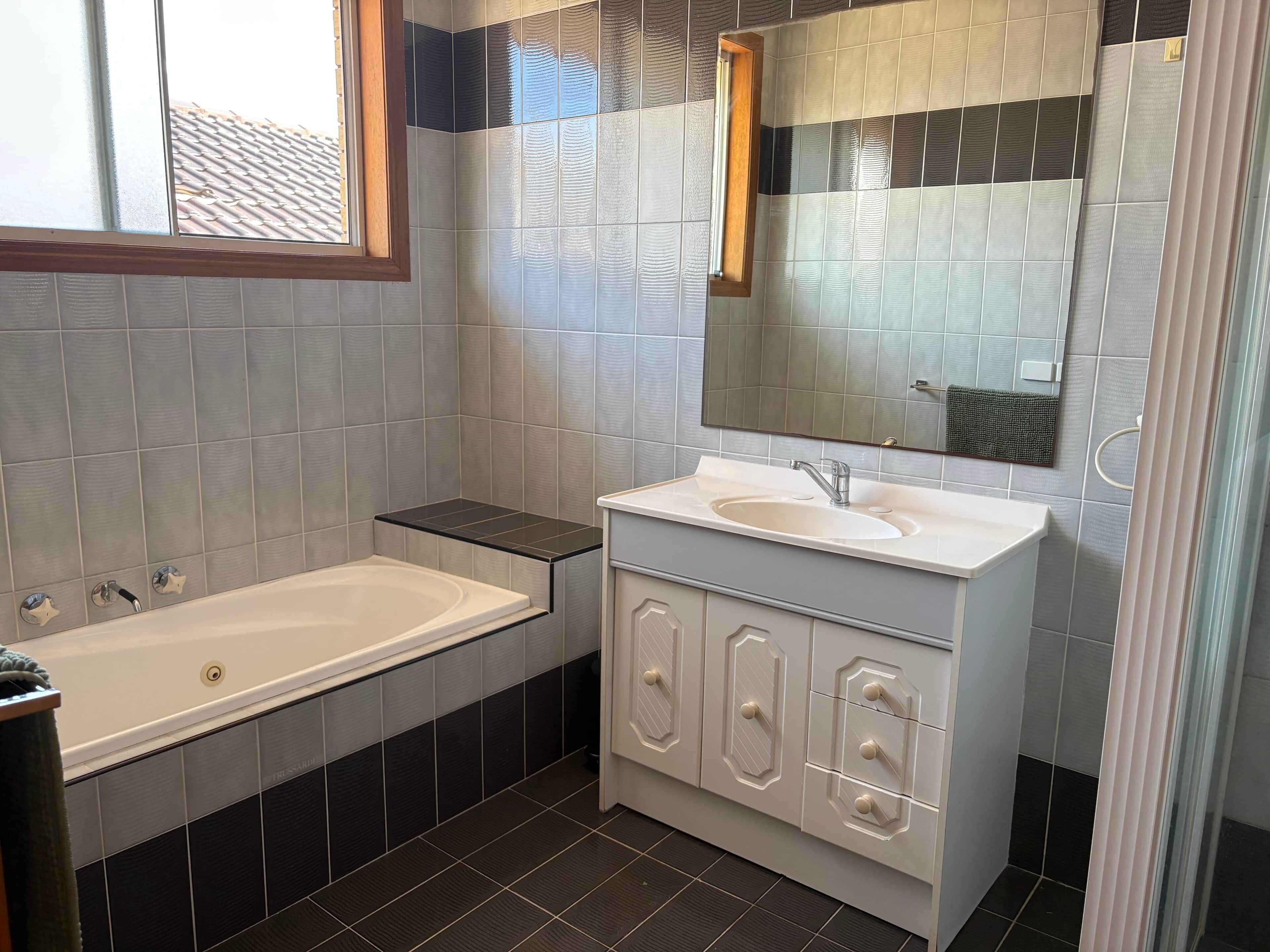 Et moderne badeværelse med badekar, vask og spejl.