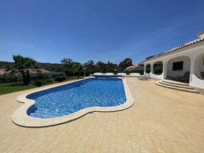 A swimming pool with a unique shape, surrounded by a tiled patio and a white building with arches. - 5-Bedroom House with Private Pool in the Algarve, Silves (Silves)
