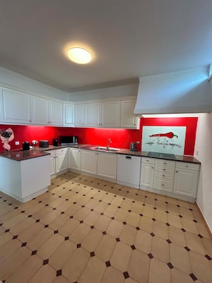 A kitchen with white cabinets, a red accent wall, and a hexagonal tile floor. - 5-Bedroom House with Private Pool in the Algarve, Silves (Silves)