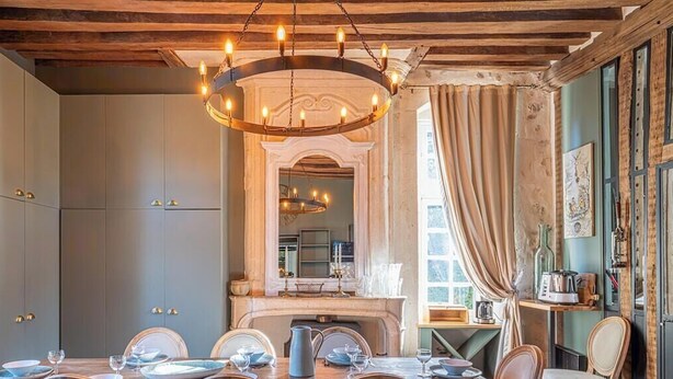 Ein Esszimmer mit einer Chandelier, Holzbalkendecke und einem Kamin.