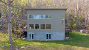 Ein zweistöckiges Haus mit Terrasse, umgeben von Bäumen und einem Rasen.