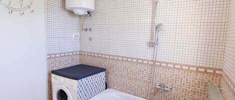 A bathroom with a washing machine, a bathtub, and a shower.