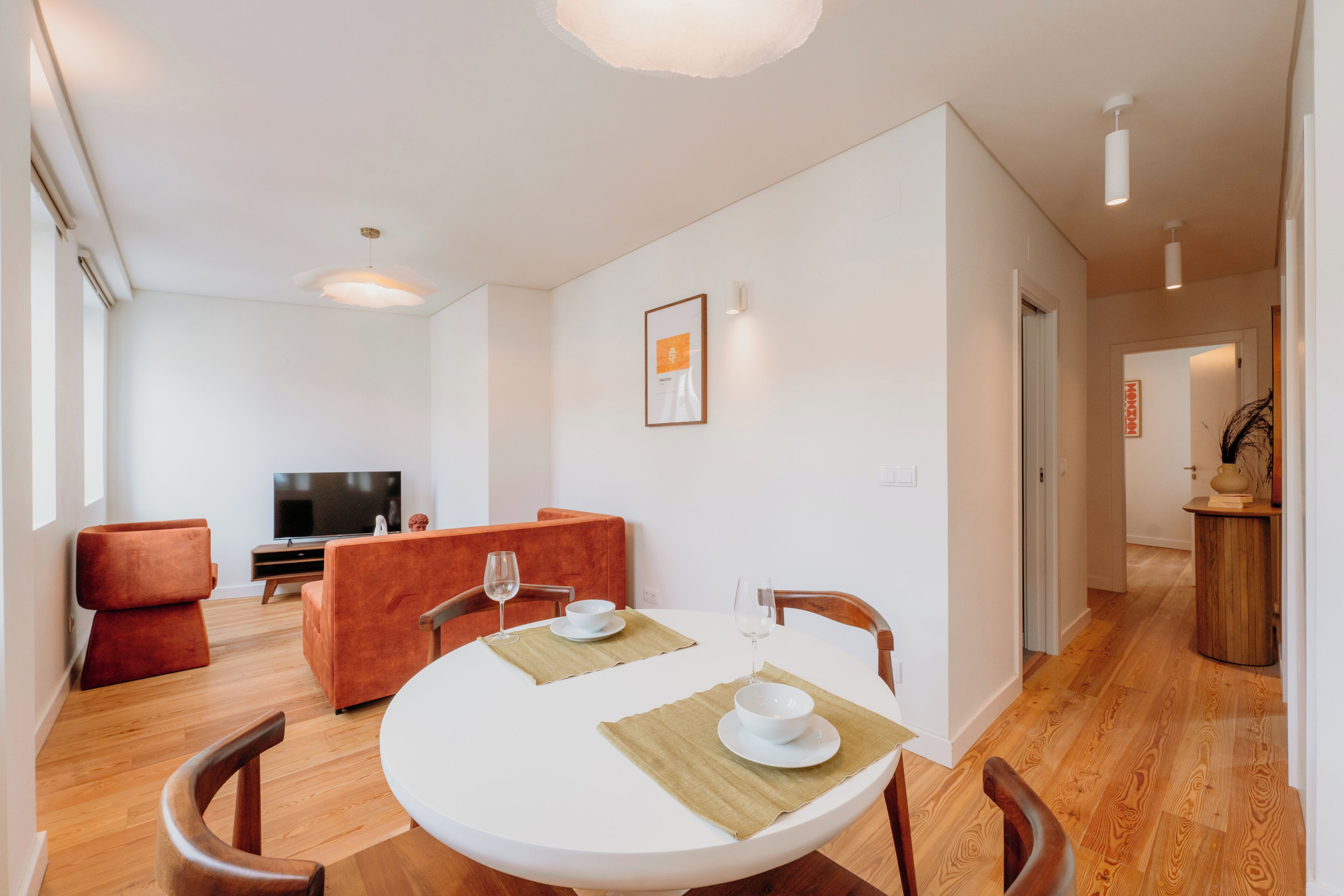 Een moderne woonkamer met een eettafel voor twee personen, een bank en een televisie.