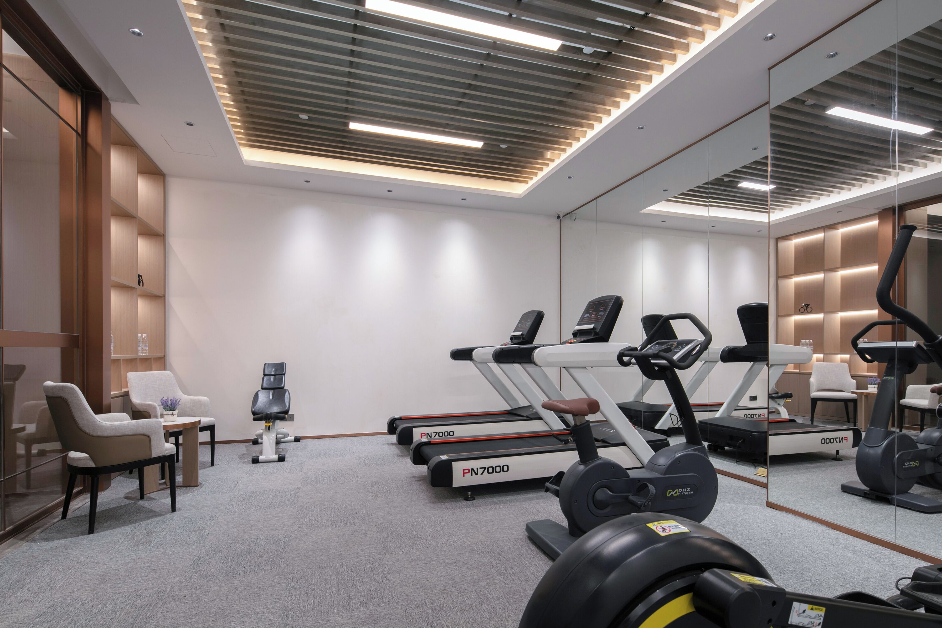 A modern gym with treadmills, a stationary bike, and a weight bench.