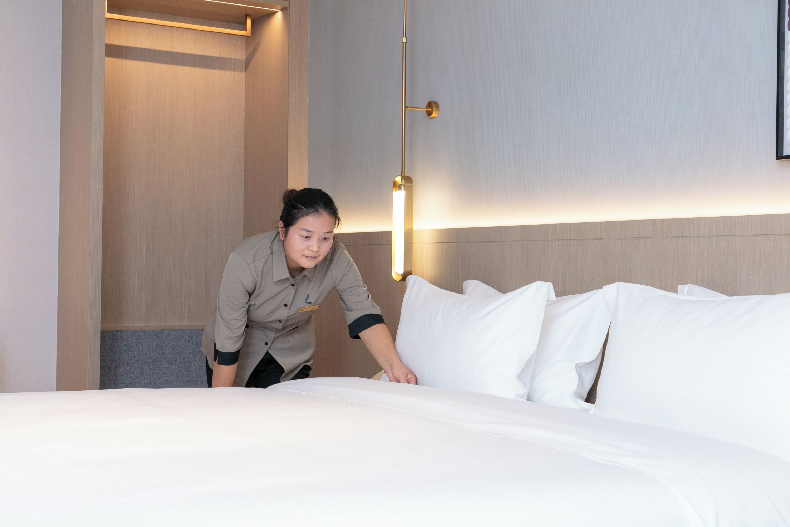 Une chambre d’hôtel avec un lit bien fait, une lampe de chevet et un luminaire fixé au mur.