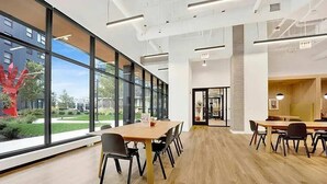 Un intérieur moderne avec de grandes fenêtres, un plancher en bois et une table de conférence entourée de chaises.