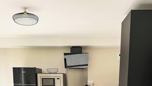 Una cucina moderna con frigorifero, microonde, forno e un piccolo angolo ristoro con una sedia e un tavolo.