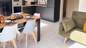 Una cucina moderna con un frigorifero Daewoo, un forno a microonde e una macchina per il caffè. C'è un tavolo da pranzo con sedie e una ciotola di cibo.