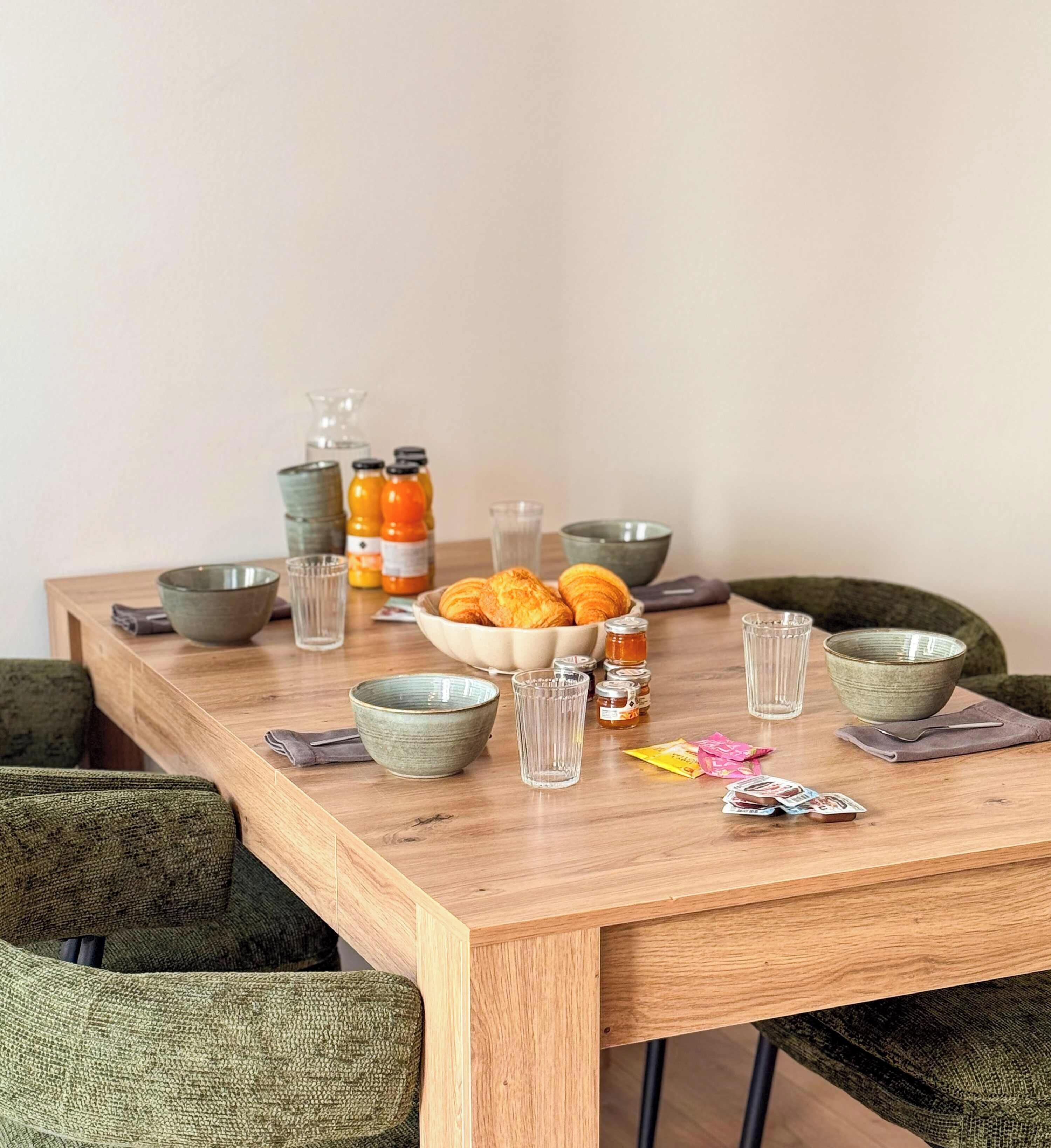 Uma mesa de jantar de madeira com tigelas, copos e alimentos.