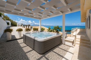 A hot tub in a covered outdoor area with a view of the sea. - Amira Beach Villa by LeDhome (Trappeto)