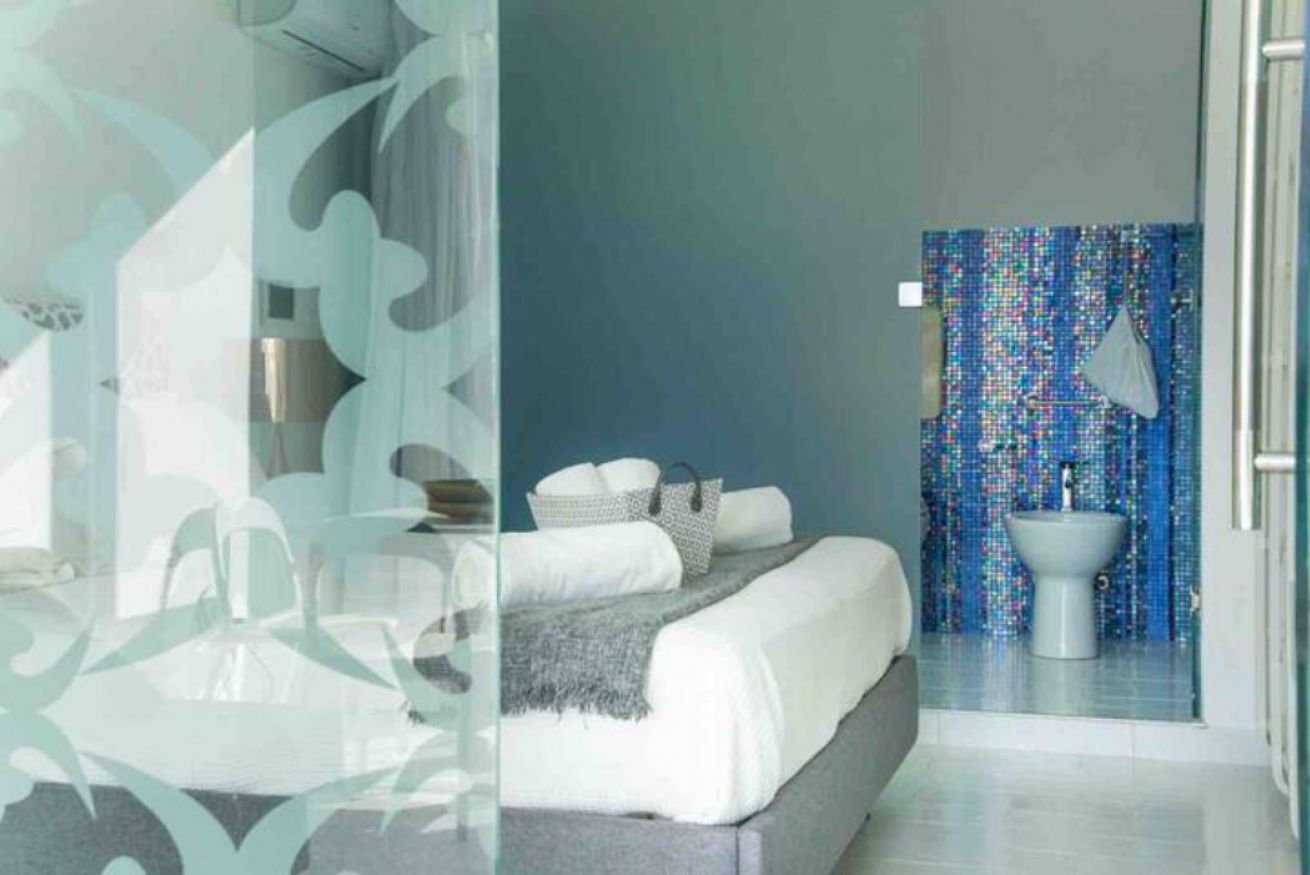A modern bathroom with a mosaic tile wall, a white sink, and a glass shower enclosure.