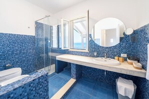 Ein modernes Badezimmer mit Duschkabine aus Glas, einem weißen Waschbecken und einem großen Spiegel.