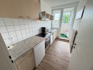 A compact kitchen with white cabinets, a built-in oven, and a coffee maker.