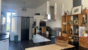 Una cocina moderna con una isla central, luces colgantes y una estantería de madera.