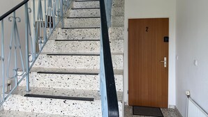 Metallikaiteilla varustetut portaat, numero 2 -merkinnällä varustettu puuovi ja seinässä oleva patteri.