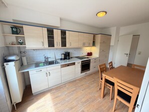 Una cocina compacta con fregadero, estufa y comedor con mesa y sillas.