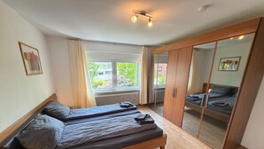 Un dormitorio con dos camas, un armario, una ventana con cortinas y un radiador.