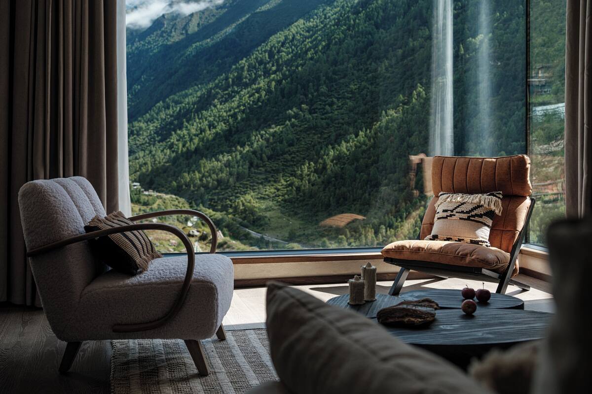 Ein Zimmer mit Blick auf Berge, eine Couch, ein Sessel und ein Tisch mit Äpfeln.