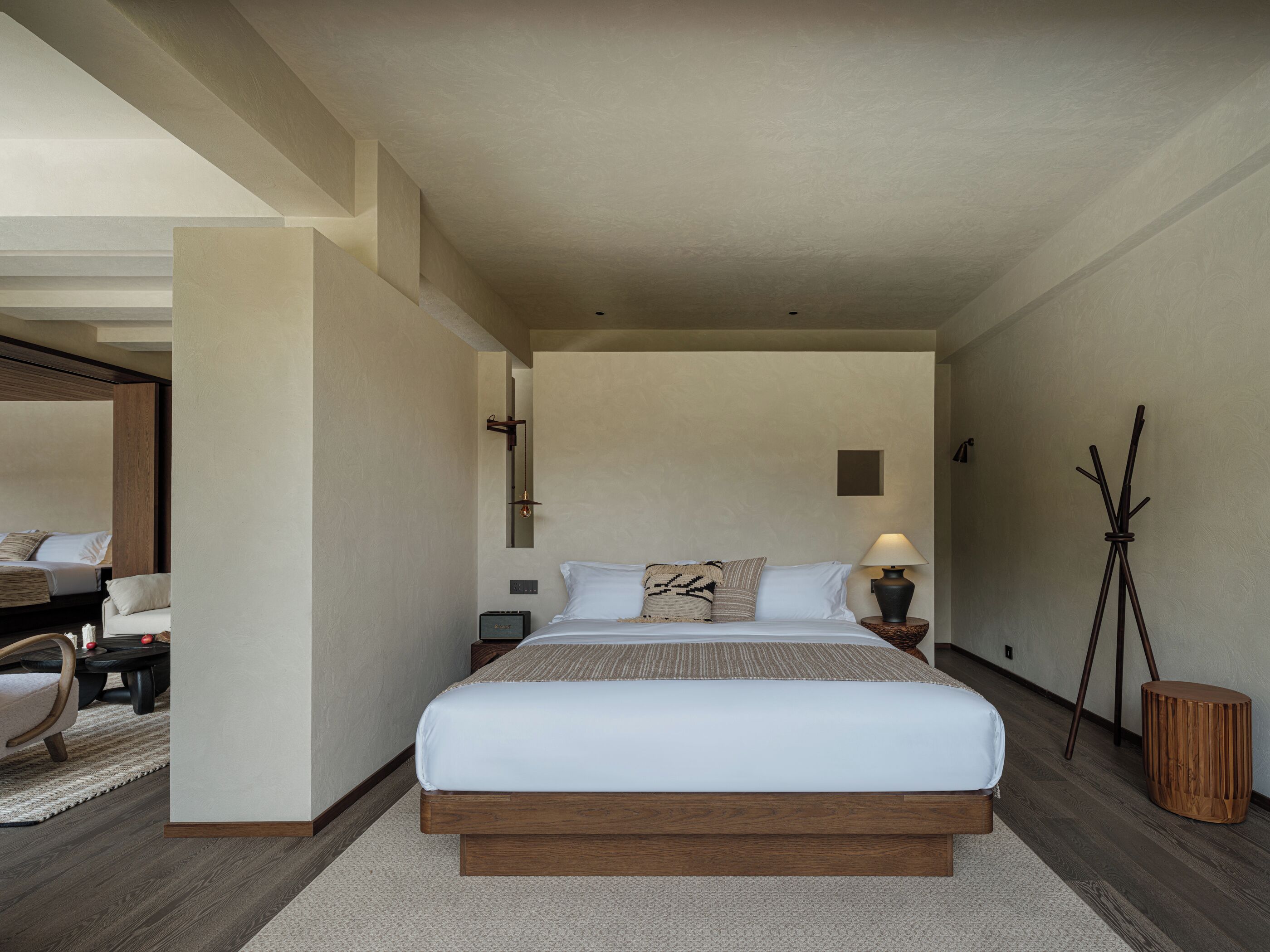 A modern bedroom with a large bed, bedside tables, a lamp, and a mirror.
