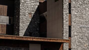 Un edificio moderno con muros de piedra y detalles de madera, que presenta una entrada amplia y una escalera que conduce a la entrada principal.