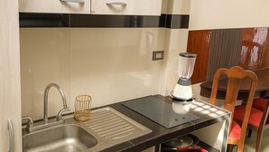 A compact kitchenette with a sink, a blender, and a pan on the countertop.