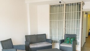 A room with wicker furniture, a tiled floor, and a sliding glass door.