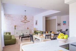 Ein modernes Wohnzimmer mit einer Couch, einem Esstisch und einer Pendelleuchte.