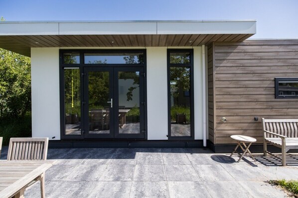 A modern building with a flat roof, large glass doors, and a wooden exterior wall.