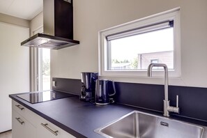 A modern kitchen with a black countertop, stainless steel sink, and a window with a view of the outside.