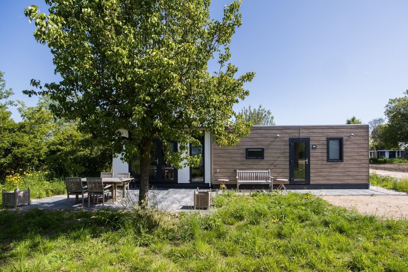 Un bâtiment moderne à l’extérieur en bois, avec un banc et une table au premier plan.