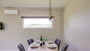 A dining area with a round table, chairs, a hanging light fixture, and a window.